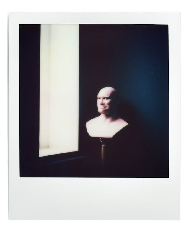 A seated figure illuminated by a window in a dark interior