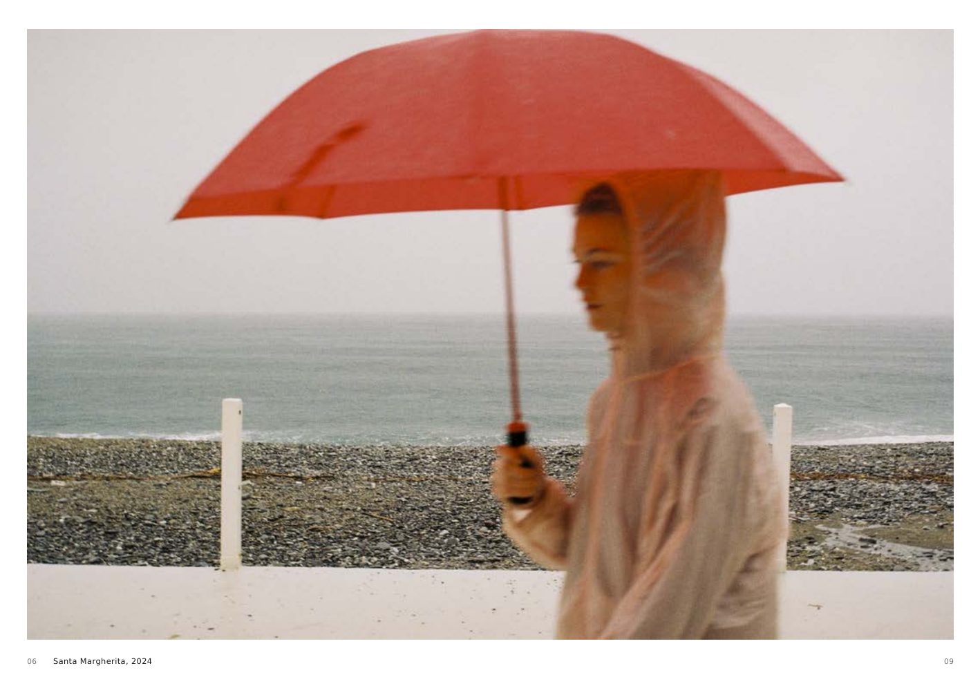 Santa Margherita, 2024, a figure beneath a red umbrella beside the sea