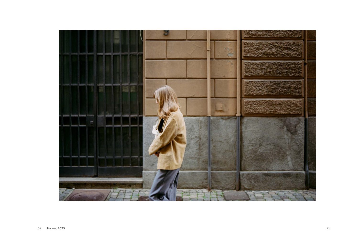 Torino, 2025, a veiled figure walking along a façade in Turin